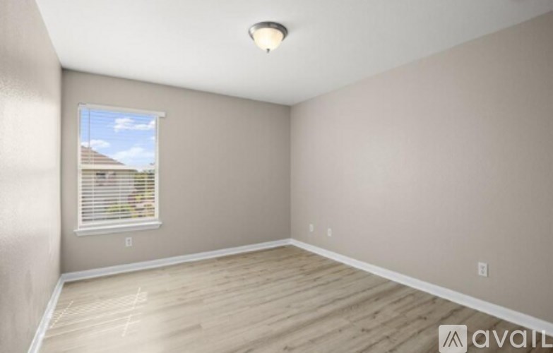 A room with wooden flooring and a window with blinds.