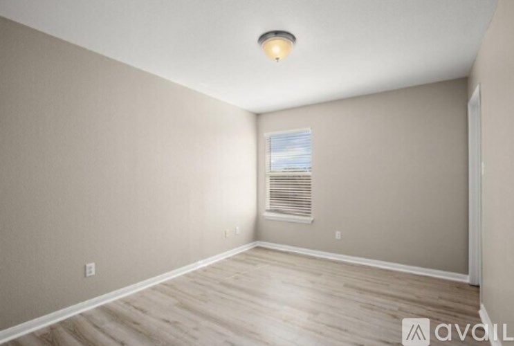 A room with a window and a wooden floor.