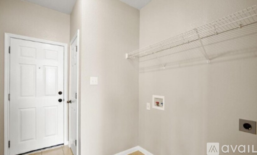 A white door is on the left of a wall with a shelf above it.