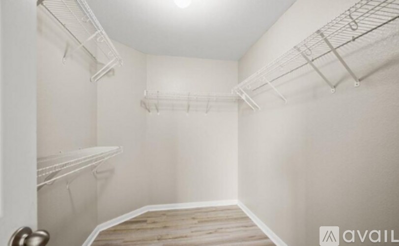 A sparsely furnished room with a white wall and a wooden floor.