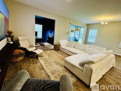 A living room with a white couch and a brown rug.