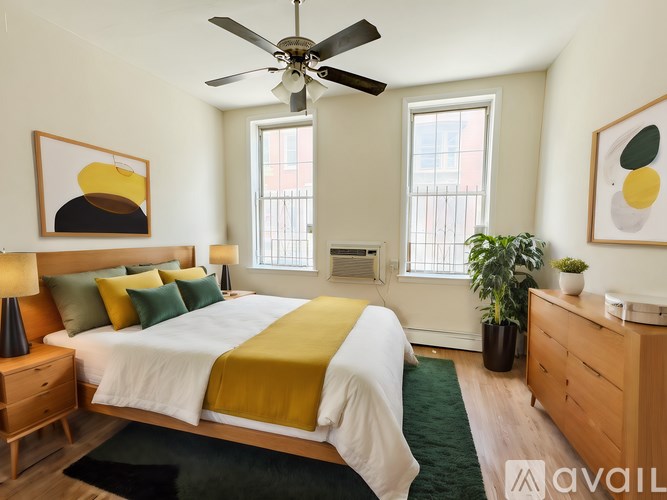 A bedroom with a bed, a ceiling fan, and two potted plants.