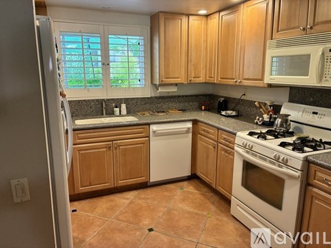 A kitchen with wooden cabinets and a white dishwasher.