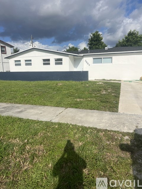 A white house with a grey roof and a black garage door.
