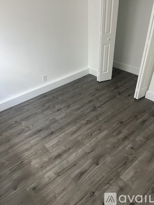 A room with wooden flooring and white walls.