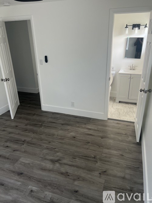 A bathroom with a white door and a wooden floor.