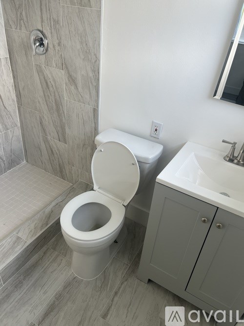 A white toilet is in a bathroom with a white sink and a walk-in shower.