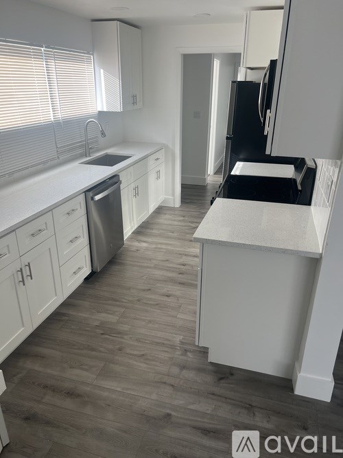 A kitchen with white cabinets and a wooden floor.