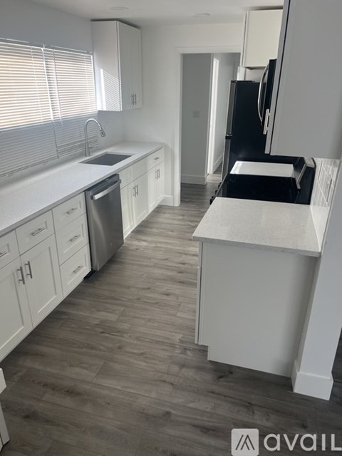 A kitchen with white cabinets and a wooden floor.