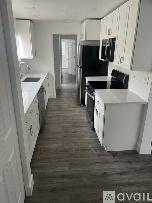 A kitchen with white cabinets and a black fridge.