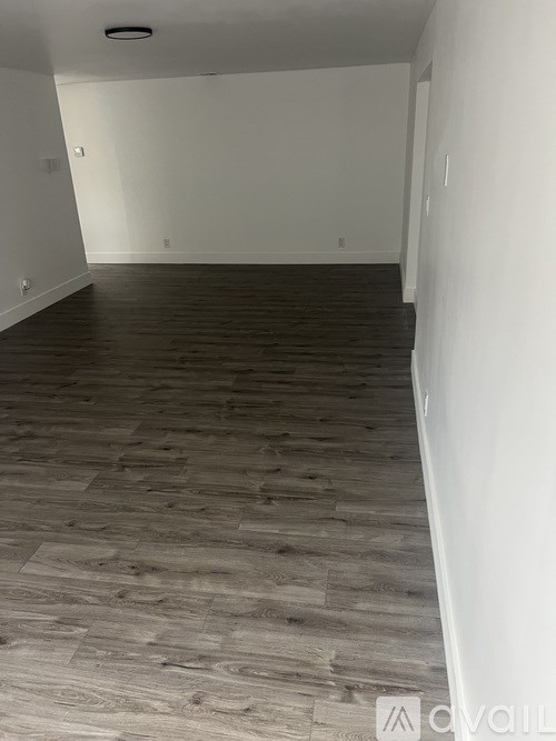 A room with wooden flooring and white walls.