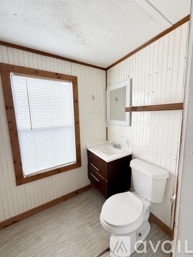 A small bathroom with a toilet, sink and window.