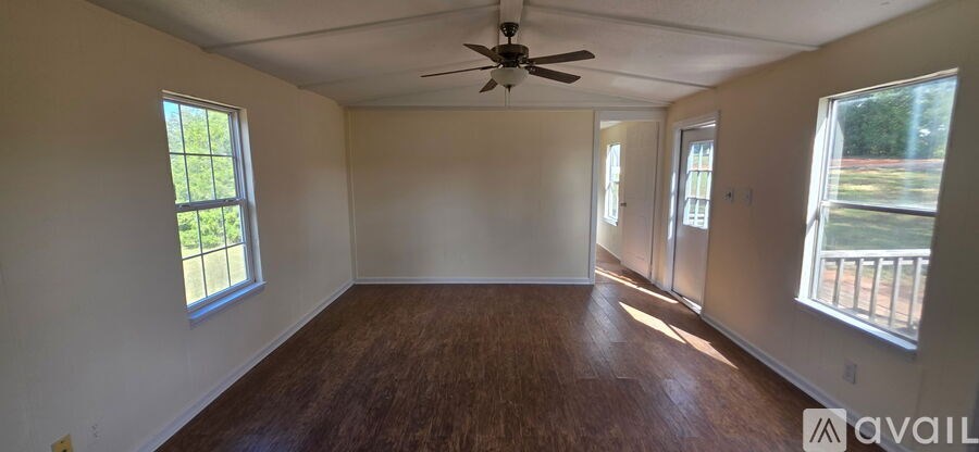 A room with a ceiling fan and two windows.