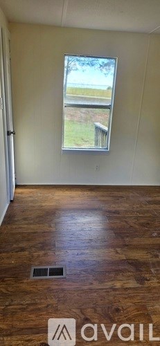 A room with a window and wooden flooring.