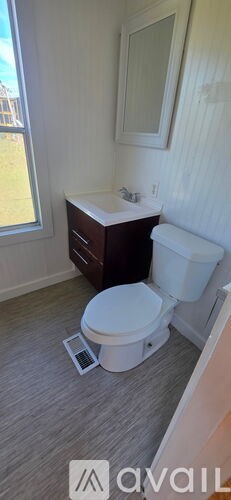A bathroom with a toilet, sink, and mirror.