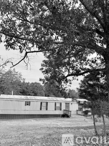 A black and white photo of a house with a tree in front.