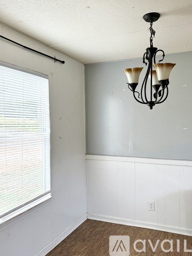 A room with a chandelier and a window with blinds.