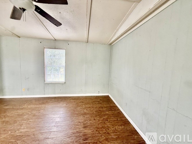 A room with a ceiling fan and wooden flooring.