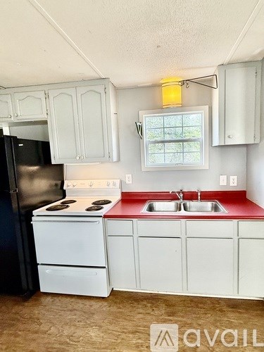 A small kitchen with a white fridge and a red counter.