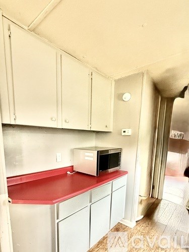 A kitchen with white cabinets and a red counter.
