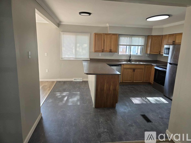 A kitchen with wooden cabinets and a dark floor.