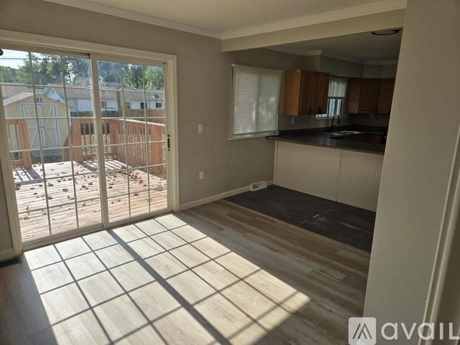 A sunny day in a kitchen with a view of a backyard through a sliding glass door.