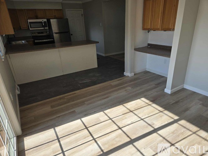 A kitchen with wooden floors and a window letting in sunlight.