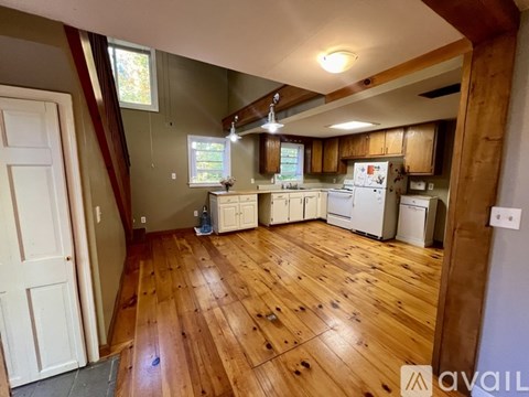 A kitchen with wooden floors and white appliances.