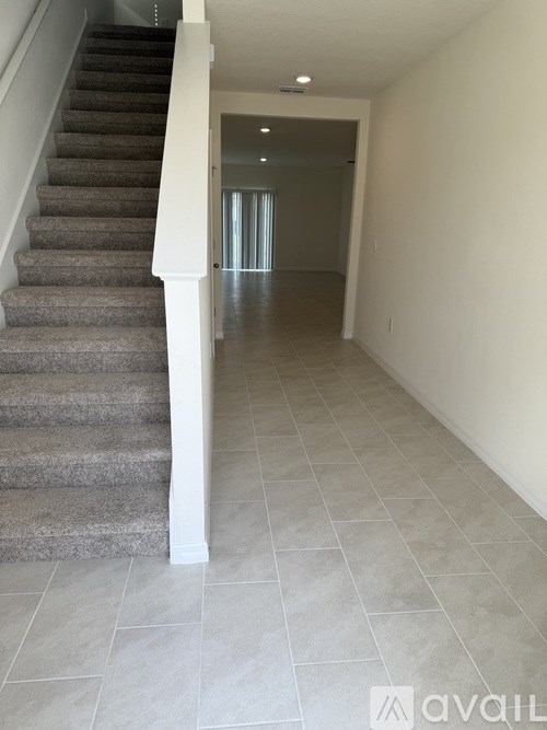 A hallway with a staircase and tiled flooring.