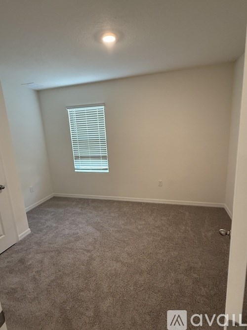 A room with a carpeted floor and a window with blinds.
