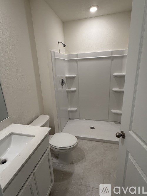 A white bathroom with a toilet, sink, and walk-in shower.