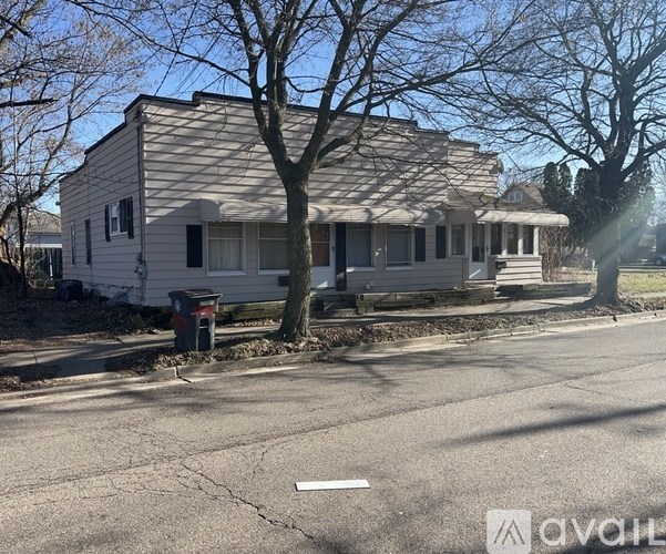 A house with a white picket fence and a tree in front of it.
