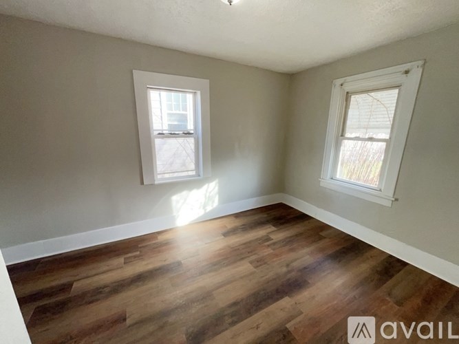 A room with wooden floors and two windows.
