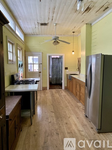 A kitchen with wooden floors and a stainless steel refrigerator.