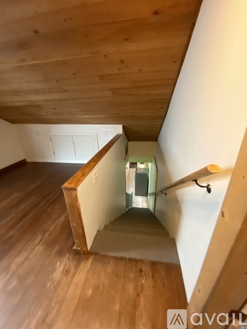 A wooden staircase with a glass railing leads up to a light at the top.