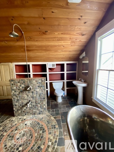 A bathroom with a wooden ceiling and a shower with a brown and tan tile floor.