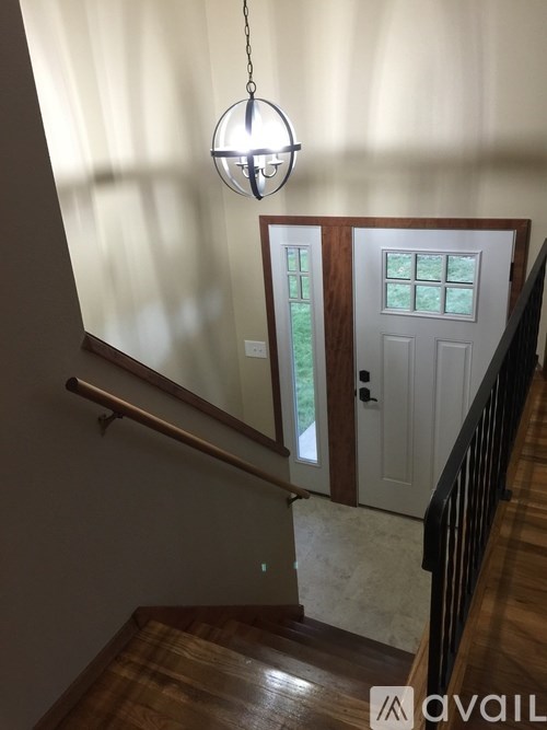 A chandelier hangs over a staircase with a white door.