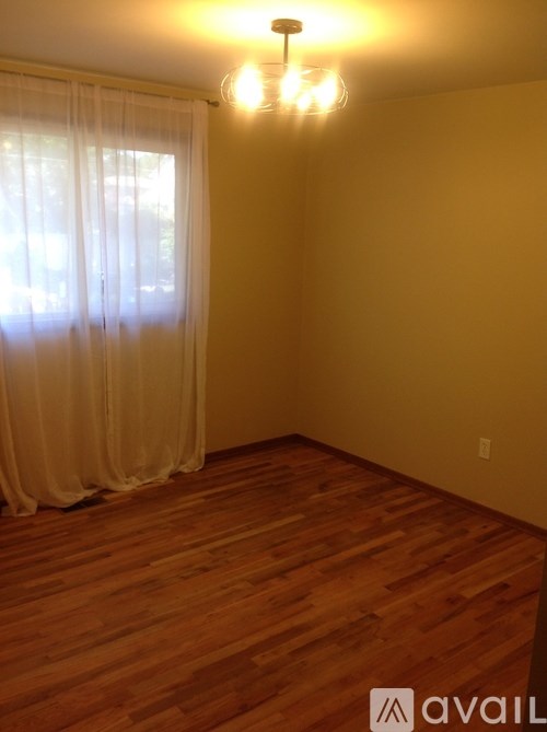A room with wooden floors and a window with curtains.