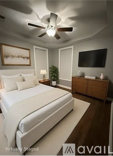 A bedroom with a bed, a ceiling fan, and a television.