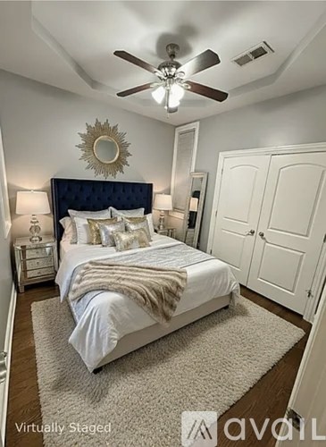 A bedroom with a bed, a ceiling fan, and a mirror.