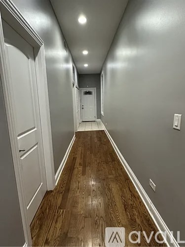 A long hallway with wood floors and white walls.