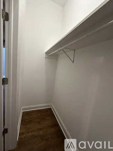 A white wall with a shelf and a door on the left.