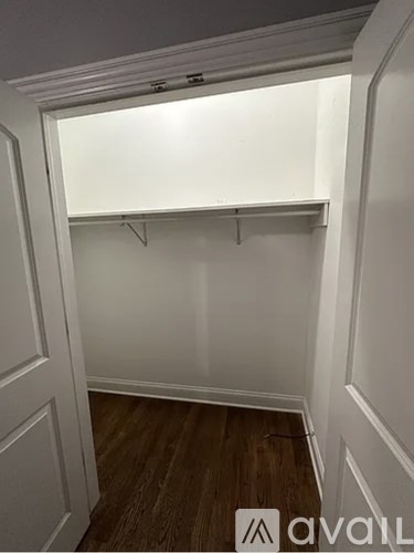 A small, empty room with a wooden floor and white walls.