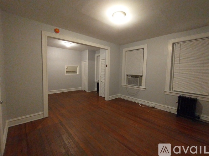A hallway with a black door and wooden floor.