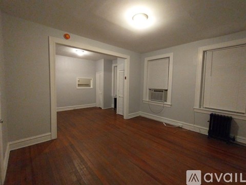 A hallway with a black door and wooden floor.