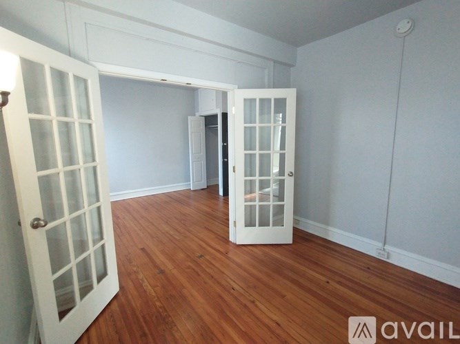 A room with a white door and a wooden floor.