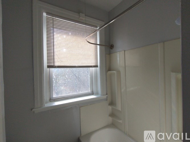 A bathroom with a window covered in blinds.