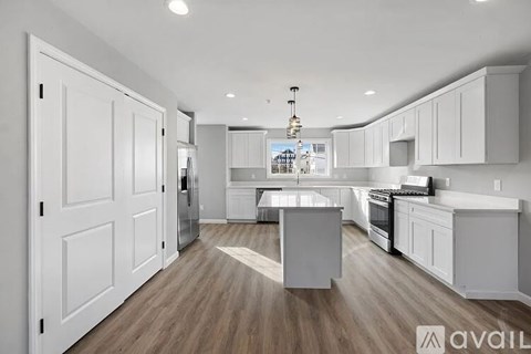 A modern kitchen with white cabinets and a wooden floor.