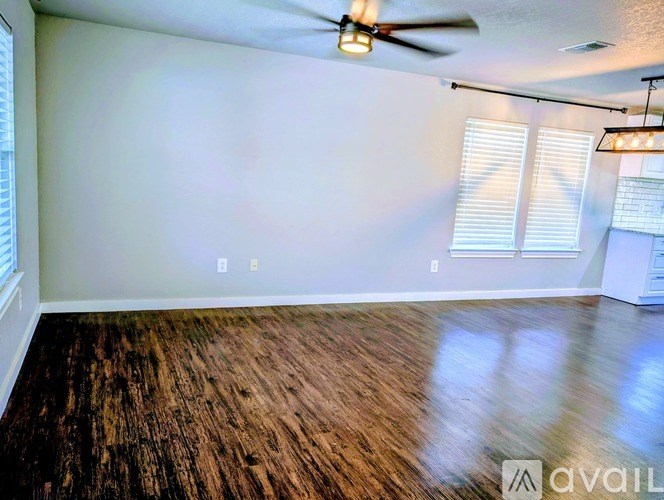 A room with a ceiling fan and wooden flooring.