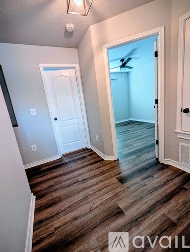 A hallway with wood flooring and white walls.